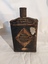 A vintage rusted black gunpowder tin with a screw top funnel lid.