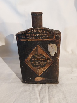 A vintage rusted black gunpowder tin with a screw top funnel lid.