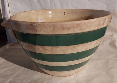 A vintage medium sized cream coloured stoneware mixing bowl with a pouring lip and three wide green stripes around it. 