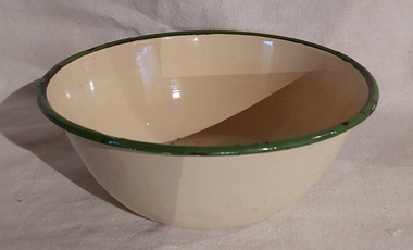 A small vintage round yellow enamel bowl with a green rim.