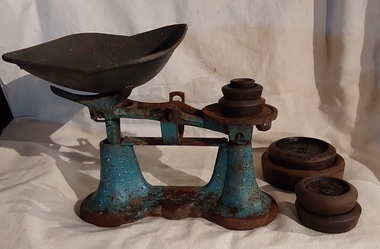 An antique blue and white speckled cast iron and metal balance scale and weights for weighing food. 
