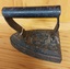 An antique heavy cast iron – sad iron with a rounded cast iron handle.