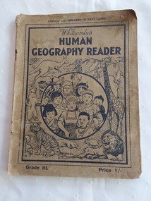 A faded green paperback reader or textbook with black lettering on the front cover at the top for the title Whitcombe's Human Geography Reader. Grade III.