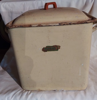 A vintage extra large cream coloured enamel bread bid with a lid and two handles on the side.