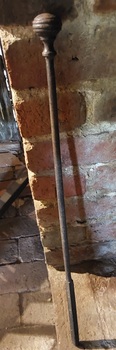 A long steel vintage fire poker with a turned knob handle and square reinforced pointed end.