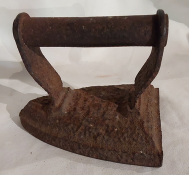 An antique heavy cast iron sad iron (from Middle English 'sad' meaning 'solid') with a rounded cast iron handle. 