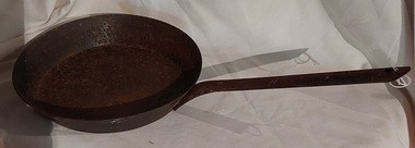 A shallow cast iron frying pan with a long tubular handle attached with three rivets to the pan. 