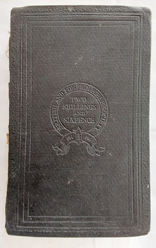 A damaged thick black hardcover Holy Bible with an embossed insignia on the front cover as well as lined patterns on the front and back covers.