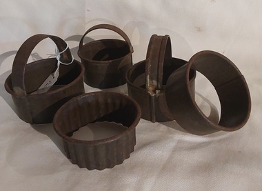 Five vintage round welded tin biscuit or pastry cutters which are all very rusted.