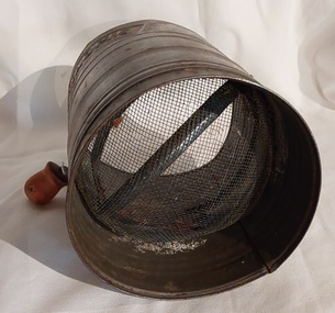 A vintage tin MAGPIE brand flour sifter with a shaped handle and a wooden knob. 