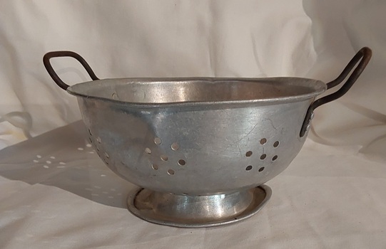 An aluminium colander with two handles welded on each side at the top.