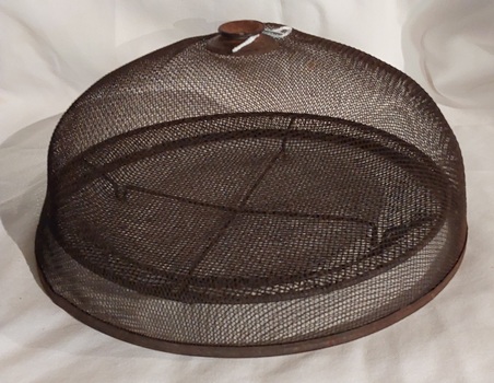 A rusted vintage wire mesh domed food cover or cloche with a rounded flat knob or handle at the top. 