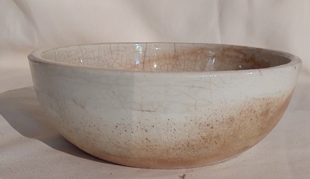 A small white crazed glazed pottery bowl used in the kitchen.