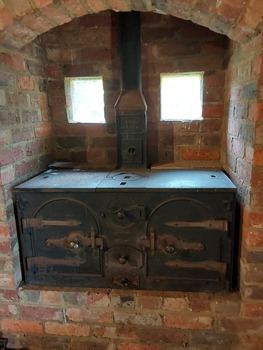 A vintage cast iron kitchen stove set in the back wall of the Mont De Lancey Slab Kitchen.