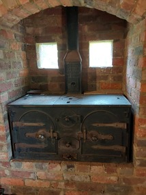 A vintage cast iron kitchen stove set in the back wall of the Mont De Lancey Slab Kitchen.