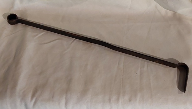 A long steel vintage fire poker with a small finger loop at the end of the handle and a bent hook shape at the end.