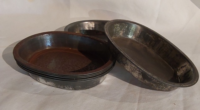 Eight vintage metal oval shaped pie dishes for use in the kitchen for baking pies.