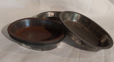 Eight vintage metal oval shaped pie dishes for use in the kitchen for baking pies.