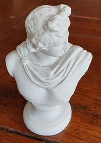 A small white resin or plaster Apollo Bust Statue which embodies beauty, music, and prophecy. 