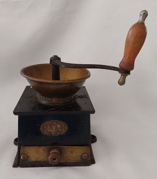Antique cast iron coffee grinder, with brass fittings and a curved winding handle with a turned wooden knob. It has a pull out drawer to collect the grinds. 