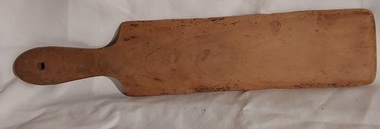 A vintage long pale wooden rectangular butter pat, with a shaped handle.