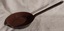 A shallow small cast iron frying pan with a long tubular handle attached with three rivets to the pan. 