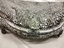 Closeup photo of purse’s semi circle frame opening, clasp with metal detailing and back of the frame lined with diamantés 
