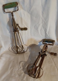 Two hand egg beaters with rotating beaters, one large, one medium. 