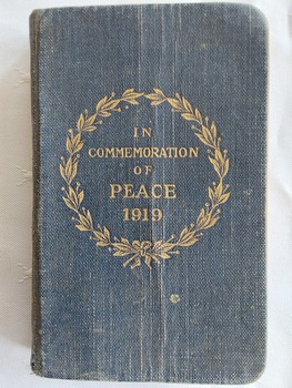 A miniature dark blue cloth covered New Testament of our Lord and Saviour Jesus Christ with a gold circular laurel wreath stamped on the front cover. 