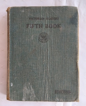 A faded dark green fabric covered hardcover with the title Victorian Reader Fifth Book printed in black lettering at the top of the front cover.