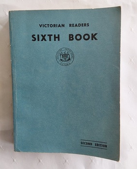 A faded blue vinyl covered softcover book with the title Victorian Reader Sixth Book, printed in black lettering at the top of the front cover.