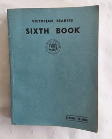 A faded blue vinyl covered softcover book with the title Victorian Reader Sixth Book, printed in black lettering at the top of the front cover.