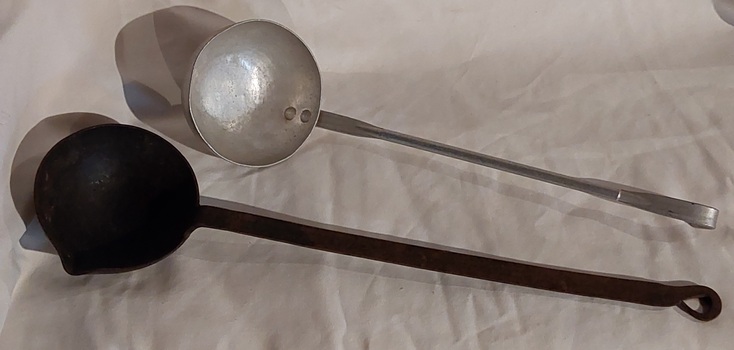 Two soup ladles for kitchen use - one is aluminium, the other is cast iron.