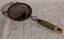 A vintage wooden handled wire mesh flour sieve or sifter with two small metal supports to rest on a bowl at the top.