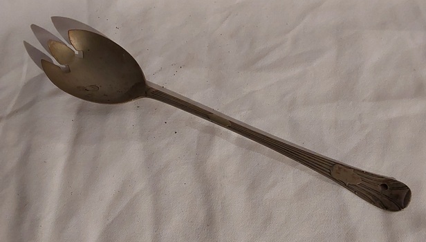 A vintage silver plated hand salad server fork with a long lined patterned handle finishing with a crest.