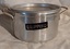 An aluminium dripping container with two side handles at the top of the rim and a removable strainer with holes. No lid.