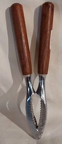 A vintage wooden two handled metal hinged nutcracker with several grooves to hold and crack hard nuts. 