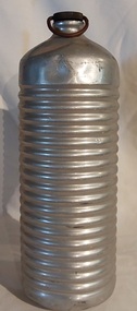 A medium sized vintage aluminium, cylindrical bed or foot warmer, with a removable brass screw stopper which has a wire looped handle on top.