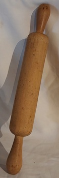 A wooden hand turned rolling pin with a shaped smaller handle at each end to hold it.