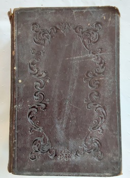 A thick black hardcover Holy Bible with an embossed large pattern on the front and back cover. 