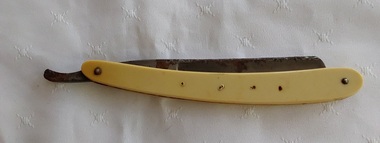 A vintage Magnetic Platypus Cut Throat Shaving Razor with a cream plastic handle which has four tiny holes on each side of it. 