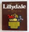 A hardcover book with a brown dust jacket with stylised illustrations of a horse, sheep, berries and trees on top of a yellow and blue rectangular truck or tractor shape.