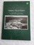 A green covered paperback book with the title printed in white, a black and white aerial photograph of the town and dam, and the author below. 