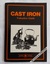 A small black covered book with the title printed in orange lettering and a photograph of cast iron including a statue and a kettle. 