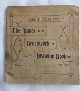 A small square faded green school Drawing Book with a decorative lined and patterned front cover.