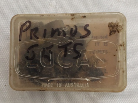 A small lidded plastic container with Primus Jet parts, washers, jet nipples, tiny open cylinders and a tiny screw.