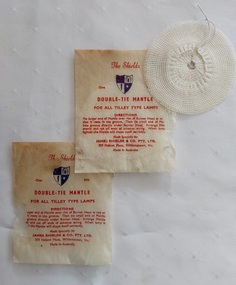Two small white paper packets containing one silk double-tie mantle for all Tilley Lamp types. 