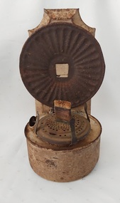 A vintage cream coloured tin wall mounted kerosene lamp for use to light the home in the 1900's. It has a shaped back support with a mounted circular reflector attached.