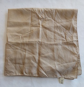 A small square beige silk scarf with machine stitched edges and a 100% cotton tag.