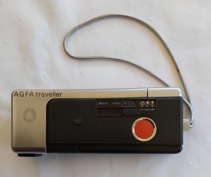 A slimline Agfa Gevaert Traveller camera made from black plastic and silver metal with  the brand stamped on the top left front.